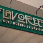 Green storefront sign reading 'FLAVOREZA' with smaller text 'BOULangerie et PATISSERIE' in metallic letters above a tiled awning