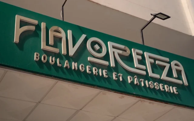 Green storefront sign reading 'FLAVOREZA' with smaller text 'BOULangerie et PATISSERIE' in metallic letters above a tiled awning